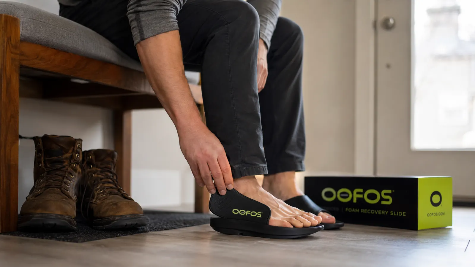 Close-up of a person slipping on a foam recovery slide after removing work boots indoors